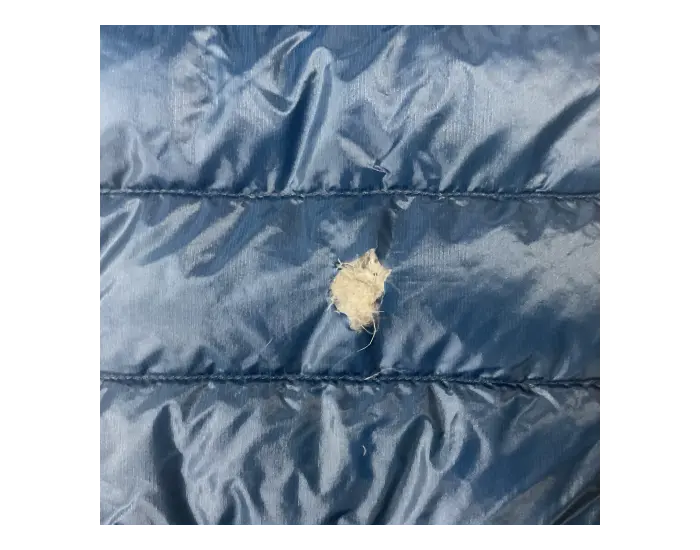 Down jacket before repair: Hole and damaged fabric.