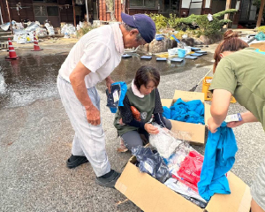 A volunteer handing relief supplies to a disaster survivor.