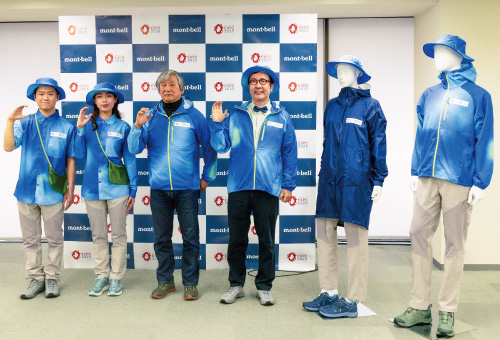 A photo showing Montbell representative Isamu Tatsuno, biologist Shinichi Fukuoka, and male and female models wearing uniforms donated by Montbell. Mannequins dressed in the donated uniforms and hats are also displayed.