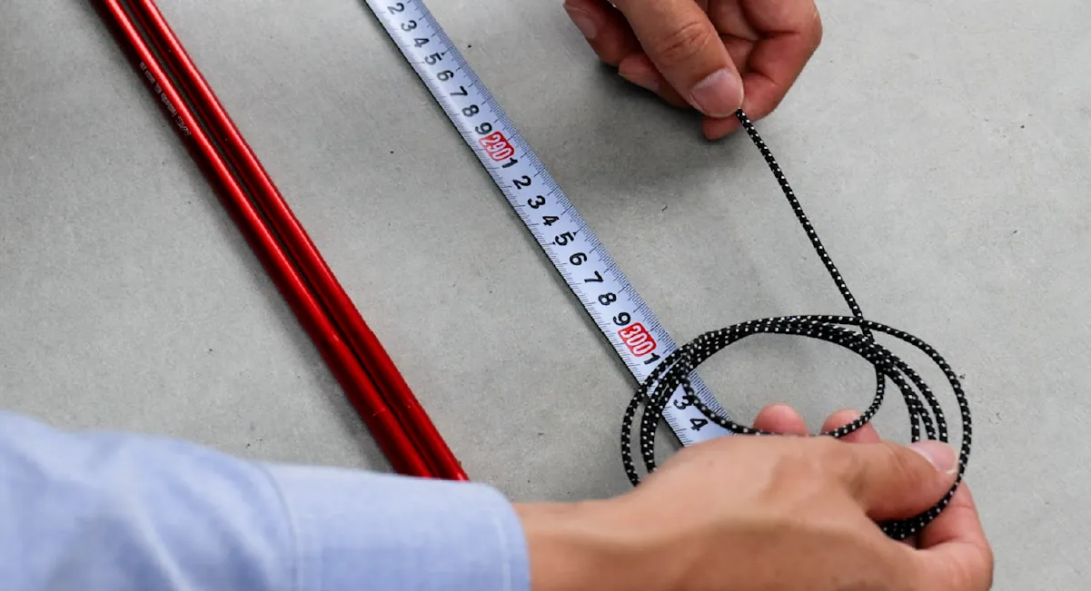 The length of the shock cord is being measured with a tape measure.