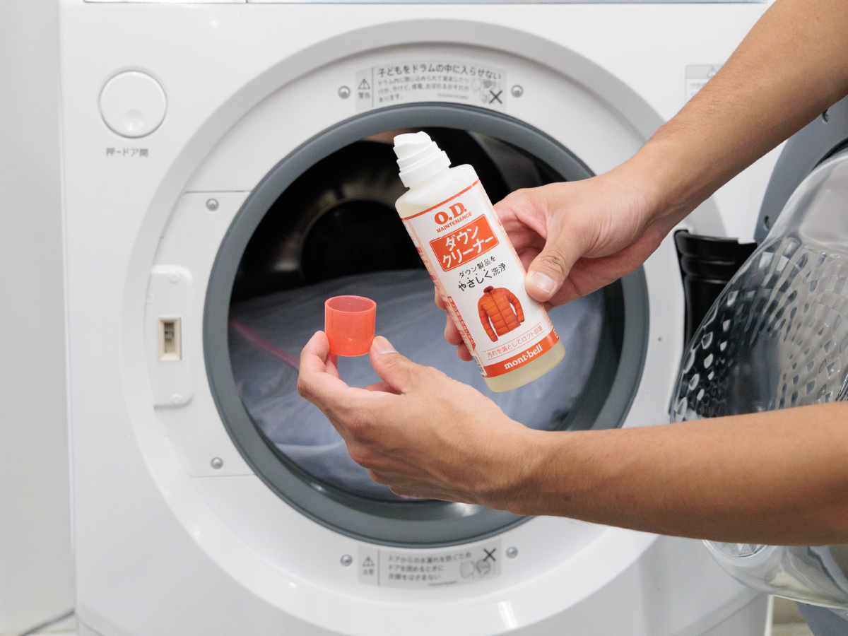 Placing down outerwear in a laundry net with down cleaner into a washing machine