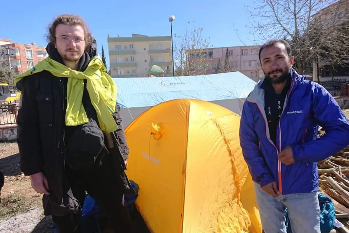 Two disaster victims standing in front of a relief supply tent.