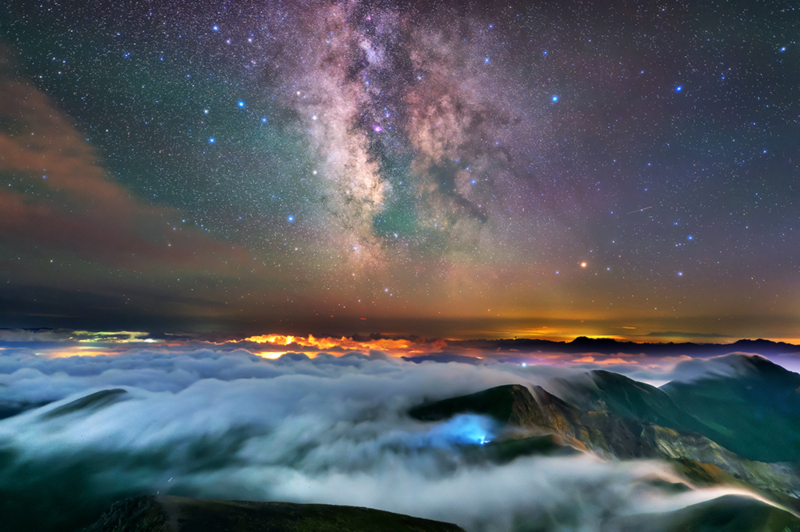 A sea of clouds spreads out like a flowing river over the mountaintop, and above it, countless stars twinkle with their light.