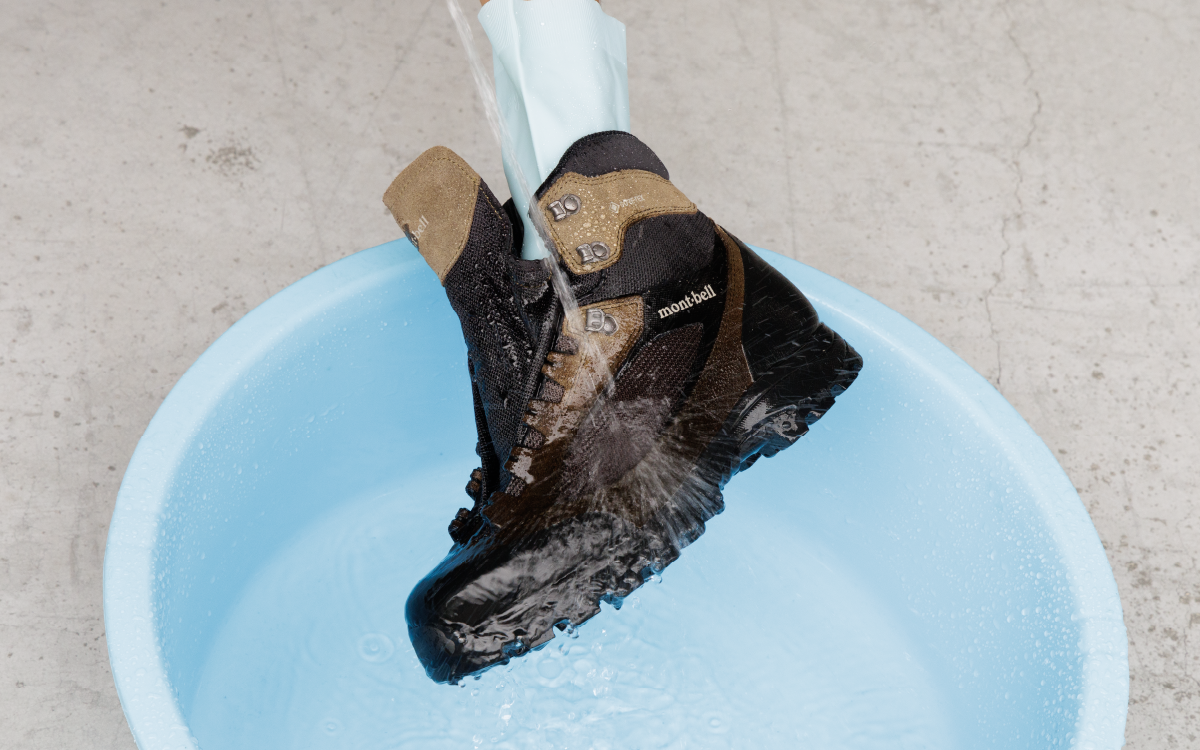 A scene depicting the process of submerging shoes in water and using a sponge to remove dirt.