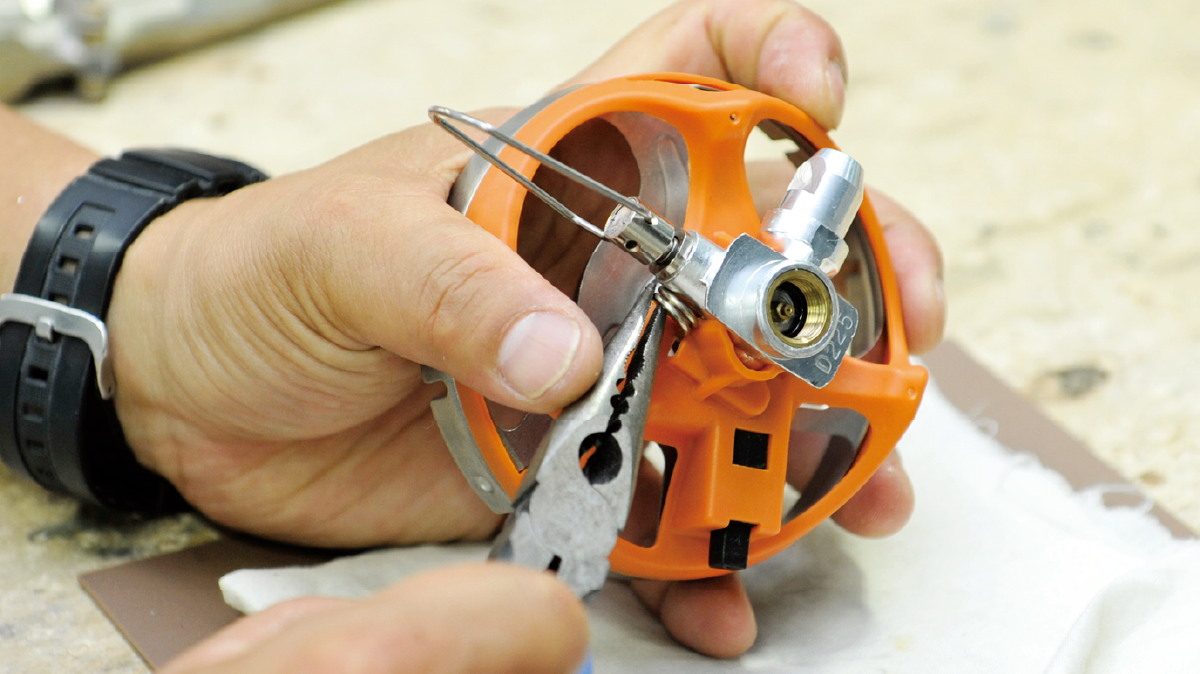 Maintaining the head of a camping stove using tools.