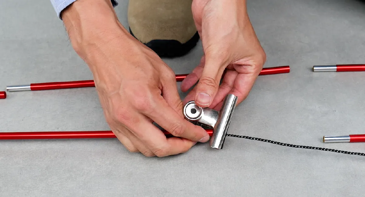 The scene illustrates the sequential threading of the new cord through the poles. To prevent accidental removal, a clip is used to secure the pole after threading it through the shock cord.