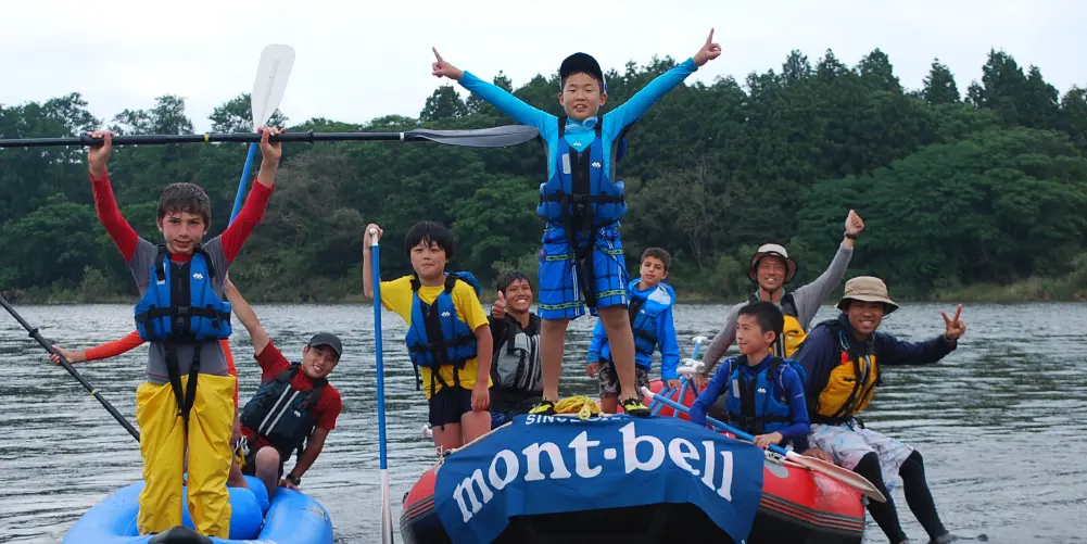 A group photo of children playing in the river on a rafting boat.