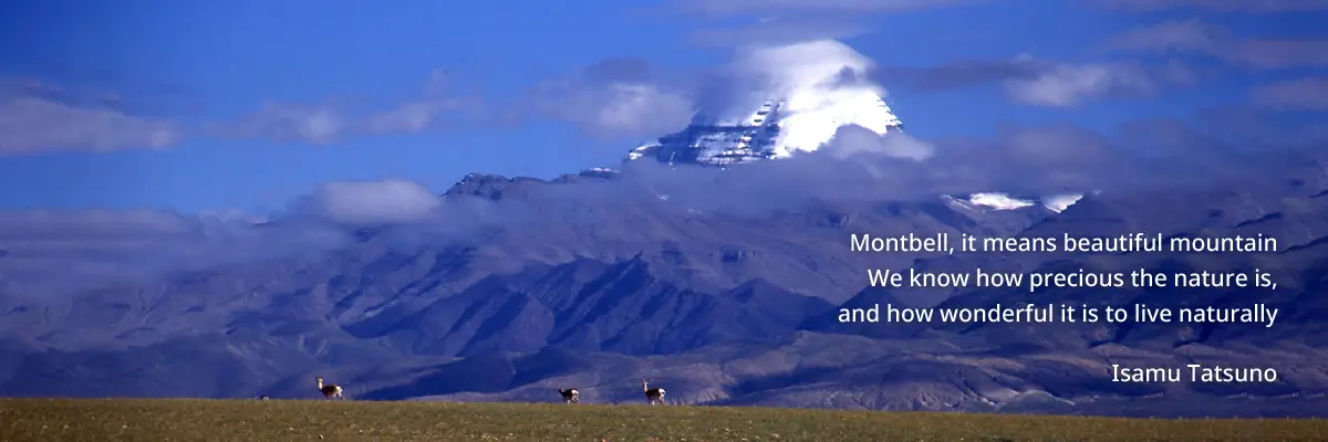 A herd of three chamois with a snow-capped mountain towering in the background. The photo includes a message from the founder, Isamu Tatsuno, which reads: "Montbell, it means beautiful mountain. We know how precious the nature is, and how wonderful it is to live naturally."