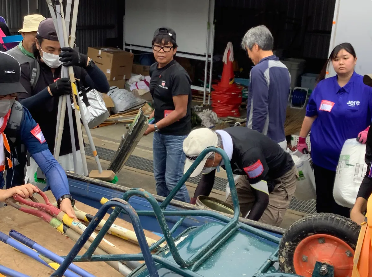Outdoor Gientai staff loading tools for debris removal onto a truck.