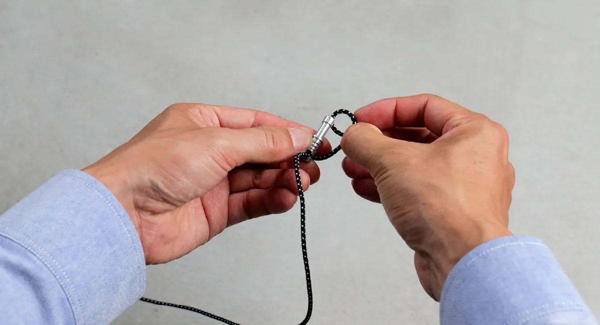 The image depicts the process of attaching a new shock cord to the end cap of the pole.