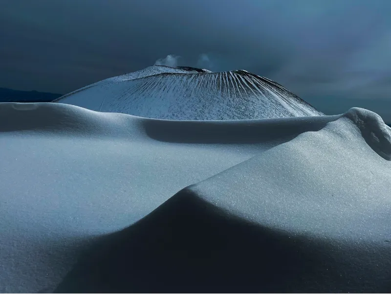 The smooth snow piled up in the foreground and the black Skin of the mountain visible in the background look like a dessert.