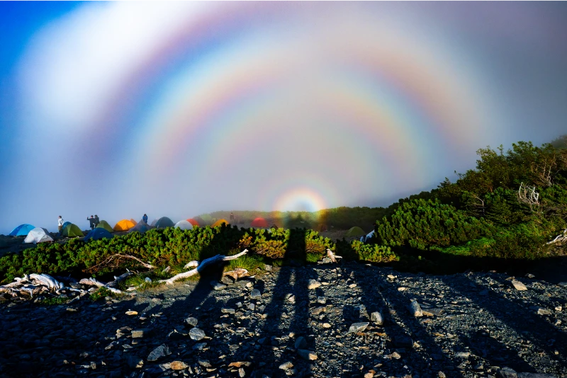 A divine light surrounds the shadows of the climbers' heads due to the Brocken spectre phenomenon.