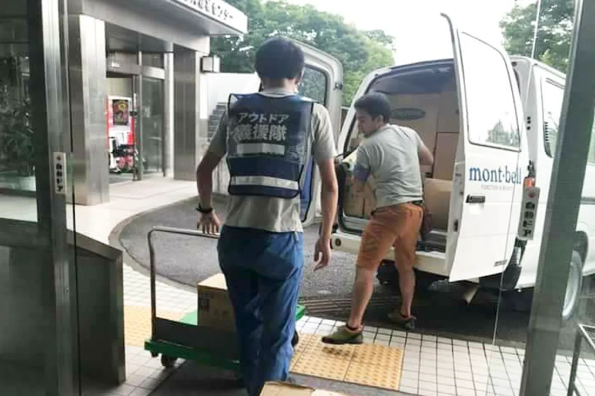 Two Outdoor Gientai staff members unloading relief supplies from a vehicle.