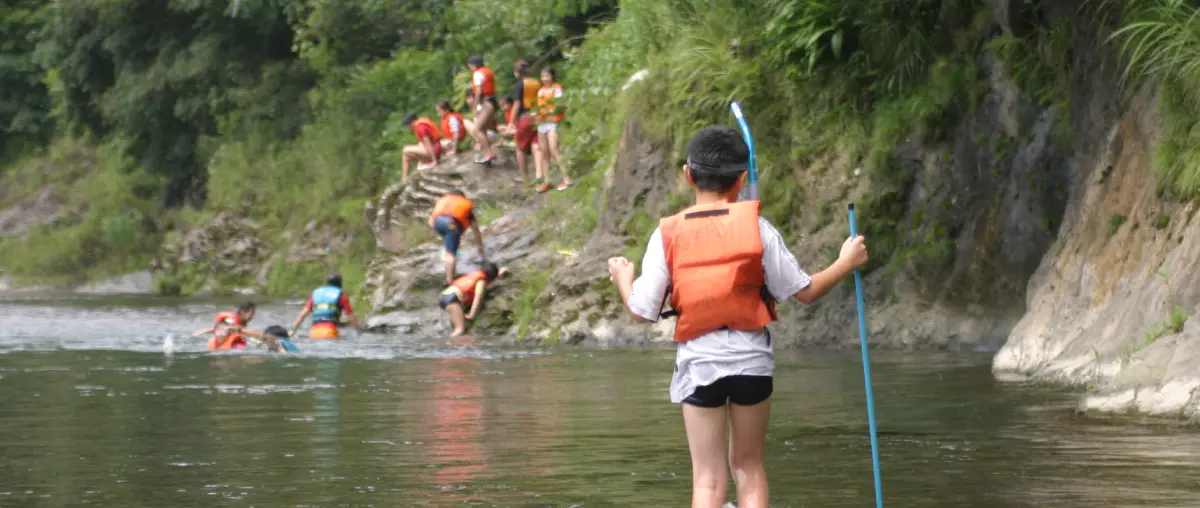 Children wearing life jackets are playing in the river.