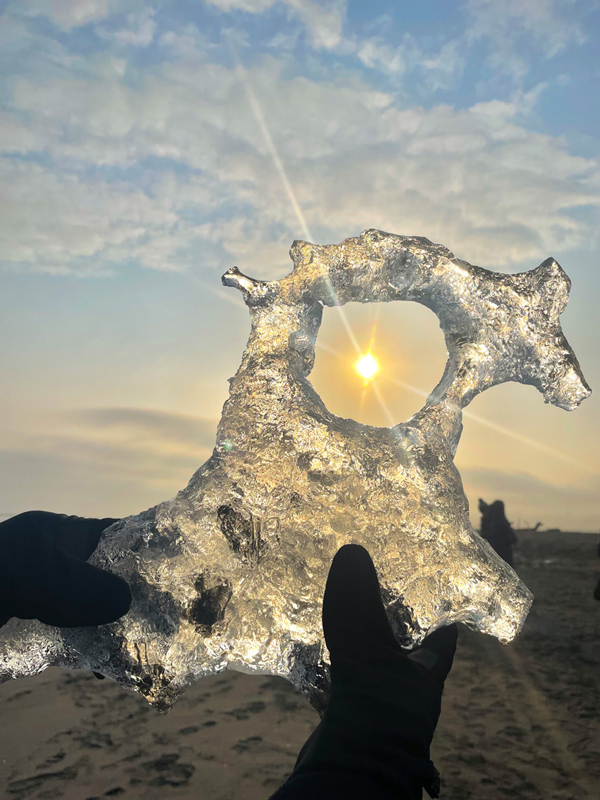 The sun sparkling through the hole of jewelry ice held in hand