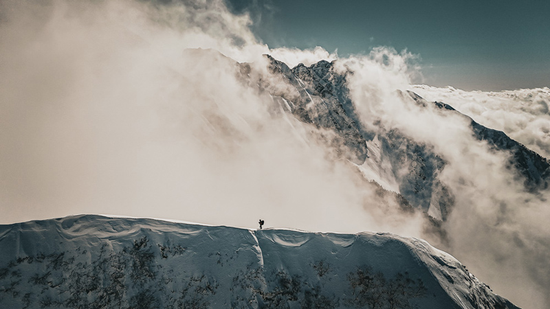 The silhouette of a mountaineer walking along a winter ridgeline