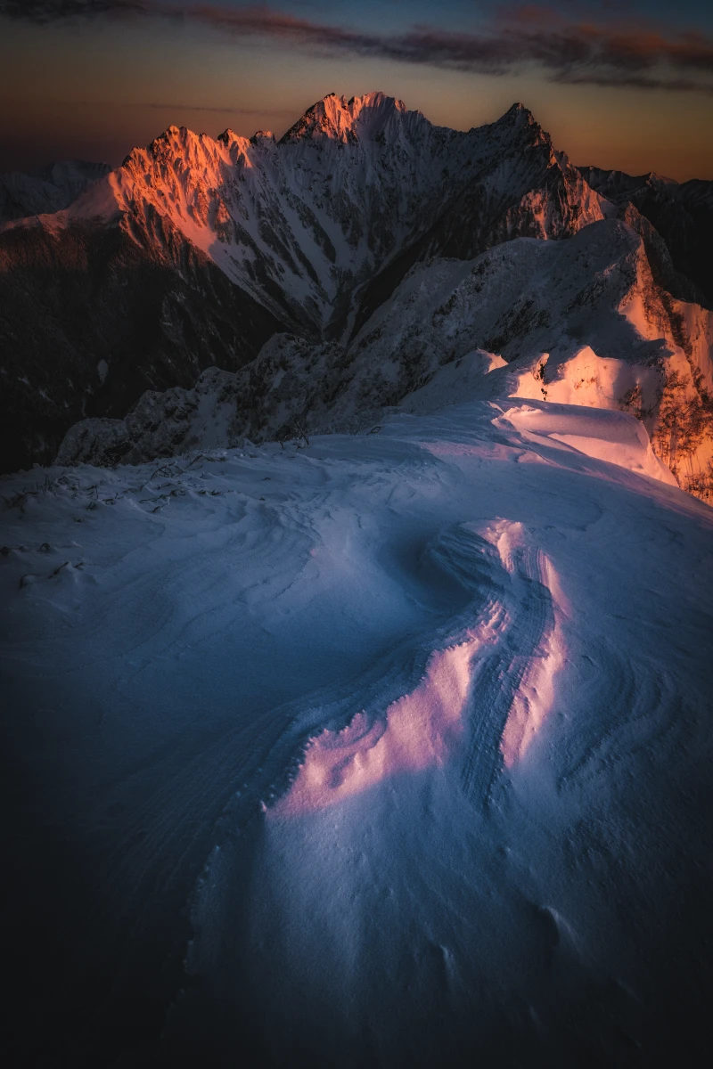 Mount Hotaka in winter. As dawn breaks, the mountain is bathed in a red glow.