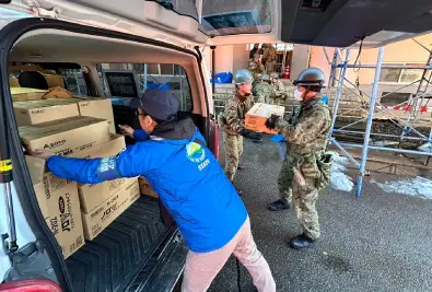 Japan Self-Defense Forces and Outdoor Gientai unloading relief supplies from a vehicle.