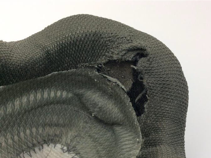 Hiking boot heel area before repair: Torn heel fabric with damaged foam.